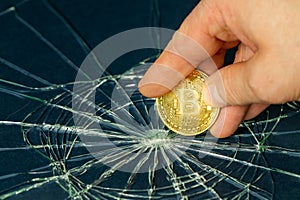 Broken window and Bitcoin held in fingers, Cryptocurrency market crash concept, Bitcoin weakening, virtual currencies