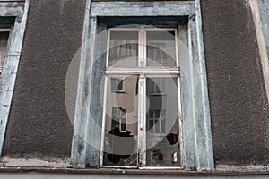 Broken window glass in abandoned old building. Dirty facade. Destruction concept. Vandalism concept. Grunge architecture exterior.