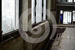Broken windows and dismantled floor in the entrance of an old abandoned apartment building