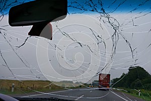 Broken windshield in the car, accident on the road with oncoming traffic, dangerous driving