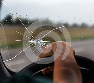 Broken windshield of a car. A web of radial splits, cracks on the triplex windshield. Broken car windshield, damaged glass with