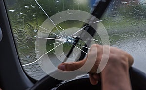 Broken windshield of a car. A web of radial splits, cracks on the triplex windshield. Broken car windshield, damaged glass with