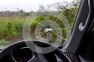 Broken windshield of a car. A web of radial splits, cracks on the triplex windshield. Broken car windshield, damaged glass with