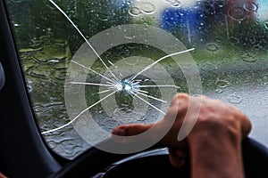 Broken windshield of a car. A web of radial splits, cracks on the triplex windshield. Broken car windshield, damaged glass with