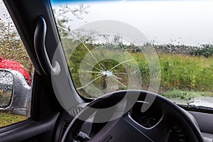 Broken windshield of a car. A web of radial splits, cracks on the triplex windshield. Broken car windshield, damaged glass with