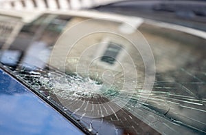 broken windshield with a lot of cracks and small glass pieces  damaged car