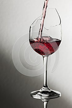 Broken wine glass with red wine pour