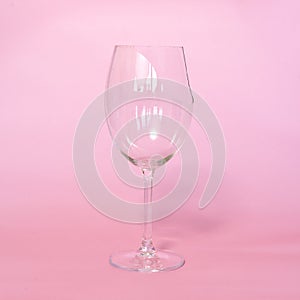 broken wine glass with shards on pink background