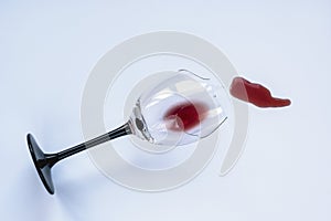 Broken wineglass with spilled red wine on white background