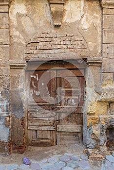 Broken wooden door on grunge stone bricks wall in abandoned street