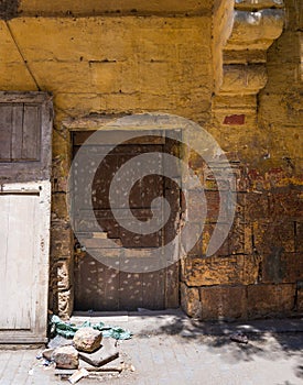 Broken wooden door on orange grunge stone bricks wall in abandoned district