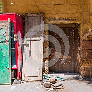 Broken wooden door on orange grunge stone bricks wall in abandoned district