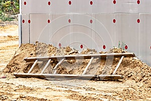 A broken wooden ladder or ladder lies on a construction site. Safety precautions for high-altitude work in construction