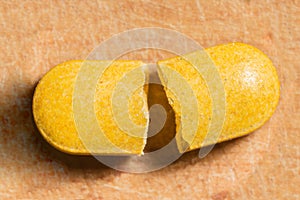 Broken yellow pill in two pieces, abstraction background