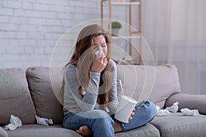 Brokenhearted young woman with bucket of ice cream crying while watching drama on TV at home