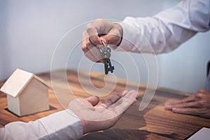 Broker agent`s hand holding House key in insurance, giving to bu