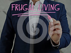 Broker writing FRUGAL LIVING on a transparent virtual interface with a marker pen