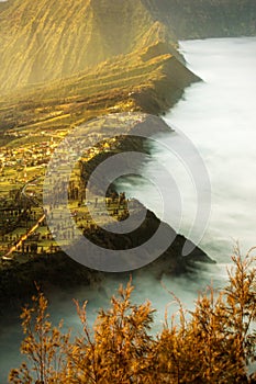 Bromo village on the mountain cliff with sunrise background and morning fog landscape at Indonesia Bromo national park