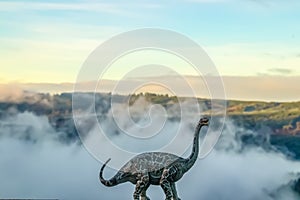 A brontosaurus or thunder lizard dinosaur roaring against a blurred misty mountain background - created with a model against natur