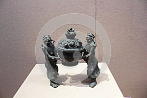 This bronze artifact depicts two figures in ancient costumes carrying a treasure basin