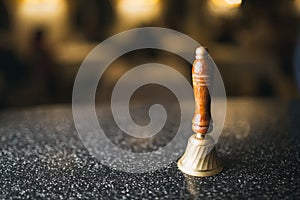 Bronze bell with wooden handle on table.