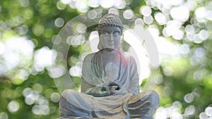 Bronze Buddha Statue in Traditional Sitting Meditation Pose on Shimmering Blurred Background