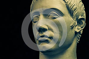 Bronze color gypsum copy of ancient statue of Germanicus Julius Caesar head for artists on black background. Renaissance