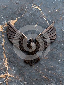 Bronze eagle sculpture on dark marble background photo