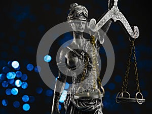 Bronze figurine of Themis - the goddess of justice on a blue background with twinkling lights. Symbol of law, justice,