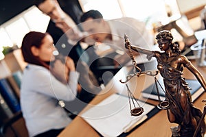 Bronze figurine of Themis holds wedding rings on scales of balance, being in foreground.