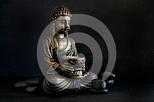 Bronze Gautama Buddha with Dark Rocks Isolated on Black