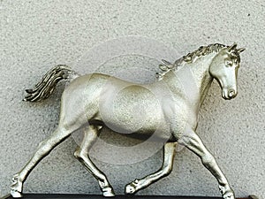 Bronze horse on the background of a concrete wall. Toned.