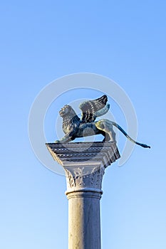 Bronze lion on the Piazza San Marco on blue sky background, Venice, Italy. Winged lion is a symbol of Venice. Ancient statue on a