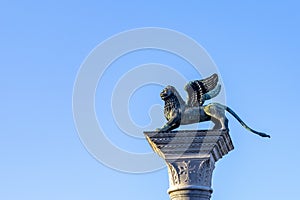 Bronze lion on the Piazza San Marco on blue sky background, Venice, Italy. Winged lion is a symbol of Venice. Ancient statue on a