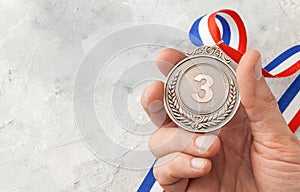 Bronze medal. A man holds a third place award with a ribbon in his hand photo