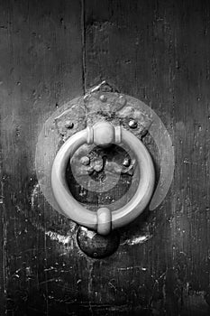 Bronze metal antique vintage door knock or knocker on an old wood door black and white