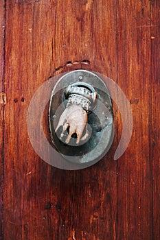 Bronze metal decoration in hand shape on an old medieval wooden door