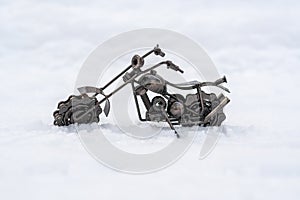 Bronze metal toy model of a road motorcycle stands on a snowy road, white background