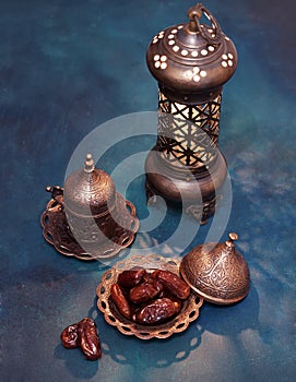 Bronze plate with dates, coffee cup, arabic lantern  on dark blue-green painted  wooden background.  Ramadan background. Toned ima