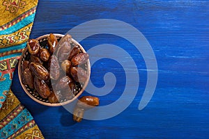 Bronze plate with dates on old blue wooden table.  Ramadan background.  Flat lay