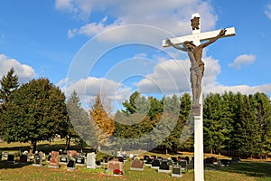 Bronze sculpture of Jesus Christ on white wooden cross at cemetery