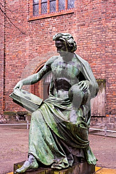 Bronze statue of The Allegory of Science, a man holding an open book and a globe, by Albert Wolff, with the Nikolaikirche behind