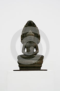 Bronze statue of a buddha kneeling in a meditative pose against a white background