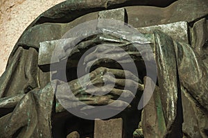 Bronze statue detail of priest hands holding a cross at Caceres