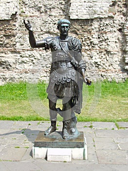 Statue of Roman Emperor Trajan in front of Roman walls in London, Uk.