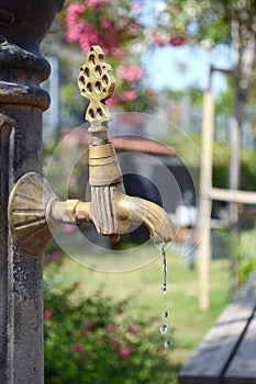 The bronze tap with flowing water on a hot summer day. Vintage faucet