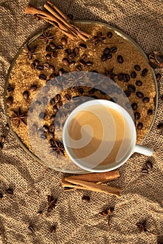 A bronze tray, with a cup of coffee, cane sugar and coffee beans, stands on a burlap