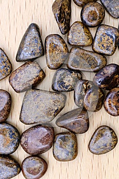 Bronzite heap up jewel stones texture on varnished wood background photo