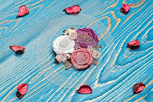 Brooch handmade consisting from of white, pink and lilac flowers making from cloth on the blue background