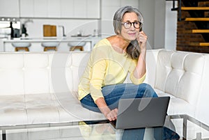 Brooding middle-aged woman using a laptop for remote work at home